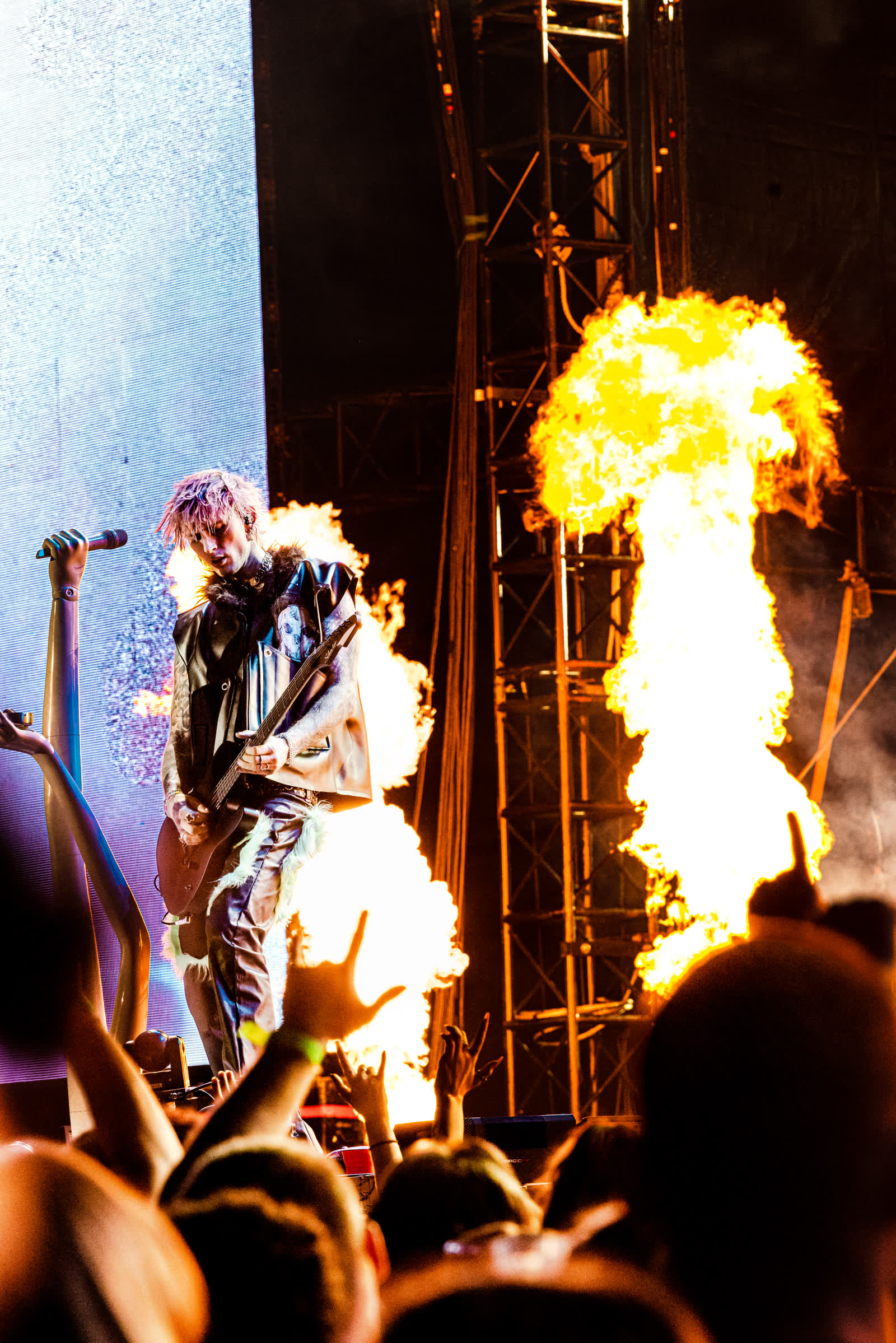 Machine Gun Kelly with guitar in front of columns of stage fire, Mainstream Sellout tour.