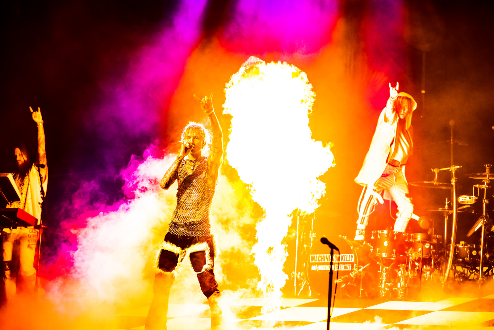 A fireball erupts center stage over the checkerboard floor, band flanking, Mainstream Sellout tour.